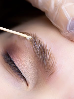 macro photography of eyebrow hairs on which laminating compounds are applied spreads them over the eyebrows with a wooden stick